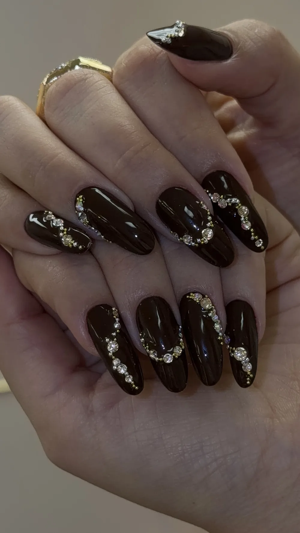Glossy dark chocolate almond nails with crystal and gold bead chains